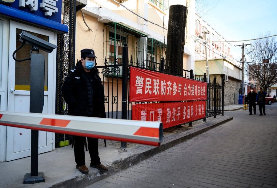 A security guard wearing a protective face mask at a compound with a banner reminding people to wear masks and wash hands in Beijing. The authorities in China were slow to act in controlling the epidemic in the initial stages. (Noel Celis/AFP)