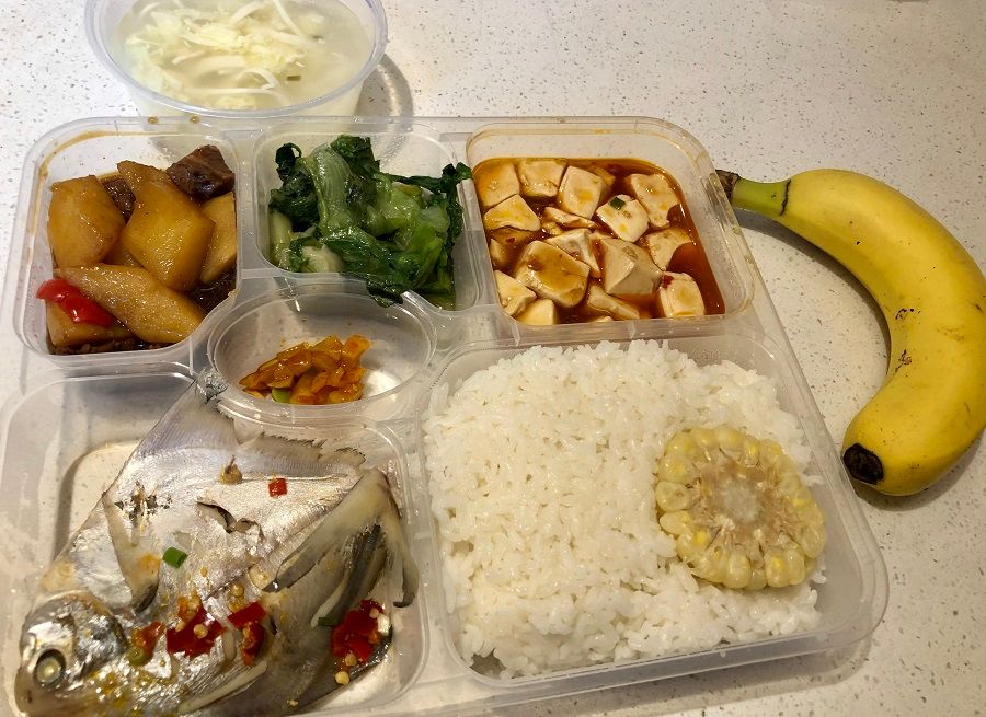 An example of lunch and dinner during quarantine: two meat dishes, two vegetable dishes, a bowl of soup, and a serving of fruit.
