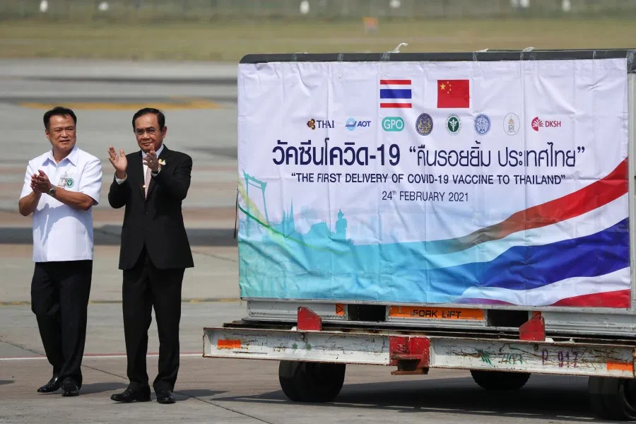 Thailand's Prime Minister Prayuth Chan-ocha and Public Health Minister Anutin Charnvirakul applaud next to a container as they attend the arrival of a plane with a shipment of 200,000 doses of the Sinovac coronavirus disease (Covid-19) vaccine from China at Bangkok's Suvarnabhumi International Airport, Thailand, 24 February 2021. (Athit Perawongmetha/Reuters)