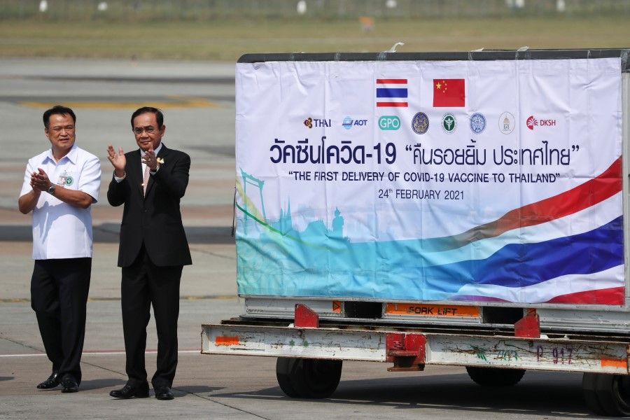 Thailand's Prime Minister Prayuth Chan-ocha and Public Health Minister Anutin Charnvirakul applaud next to a container as they attend the arrival of a plane with a shipment of 200,000 doses of the Sinovac coronavirus disease (Covid-19) vaccine from China at Bangkok's Suvarnabhumi International Airport, Thailand, 24 February 2021. (Athit Perawongmetha/Reuters)