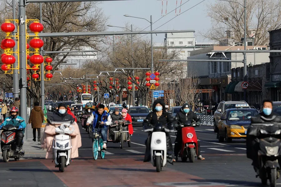 People wearing face masks are seen on a street decorated with street lights in the shape of Chinese lanterns ahead of the Chinese New Year holiday, in Beijing, China, 26 January 2021. (Tingshu Wang/Reuters)