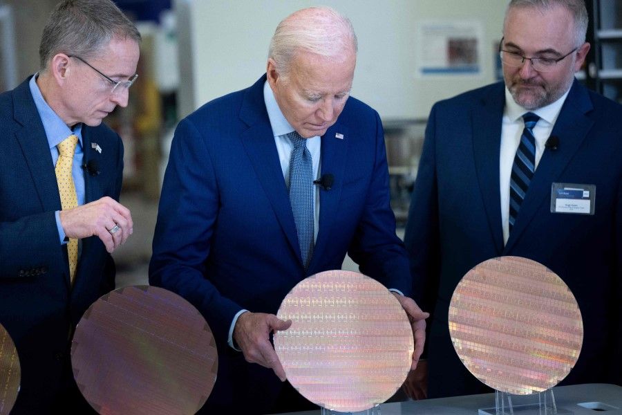 US President Joe Biden (centre) looks at a semiconductor wafer during a tour at Intel Ocotillo Campus in Chandler, Arizona, on 20 March 2024. The White House unveiled almost US$20 billion in new grants and loans to support Intel's US chip-making facilities, marking the Biden administration's largest funding announcement yet as it tackles China's dominance of the crucial technology. (Brendan Smialowski/AFP)