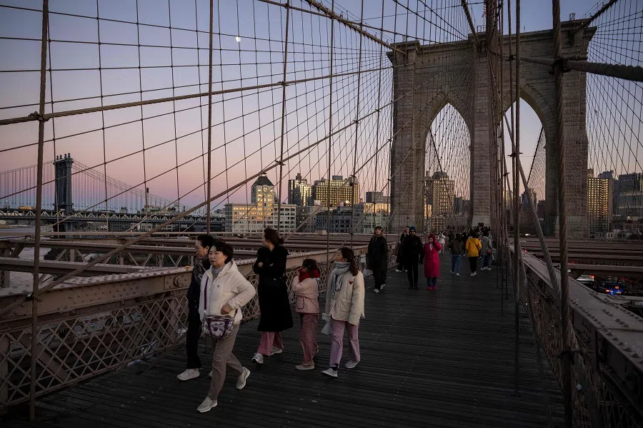 People walk over the Brooklyn Bridge in New York at dusk on 12 November 2024. (Angela Weiss/AFP)