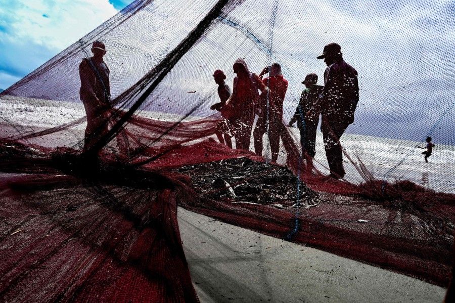 Fishermen pull in their net along the coast of Banda Aceh on 1 August 2021. (Chaideer Mahyuddin/AFP)
