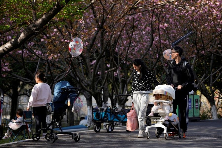 A parents pushes a stroller with a baby in a park in Shanghai, China, 2 April 2023. (Aly Song/Reuters)