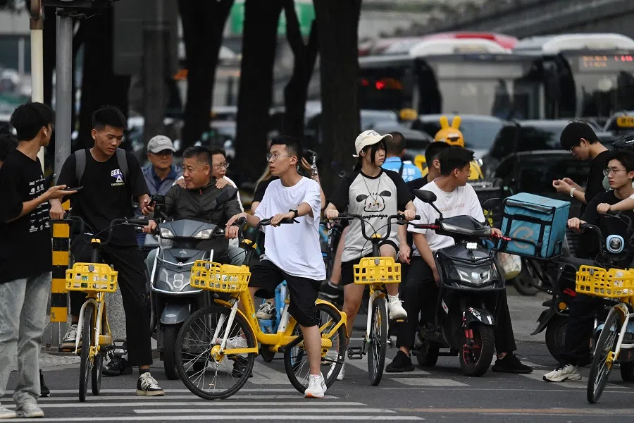 People wait to cross a road in the central business district in Beijing, China, on 7 August 2024. (Greg Baker/AFP)