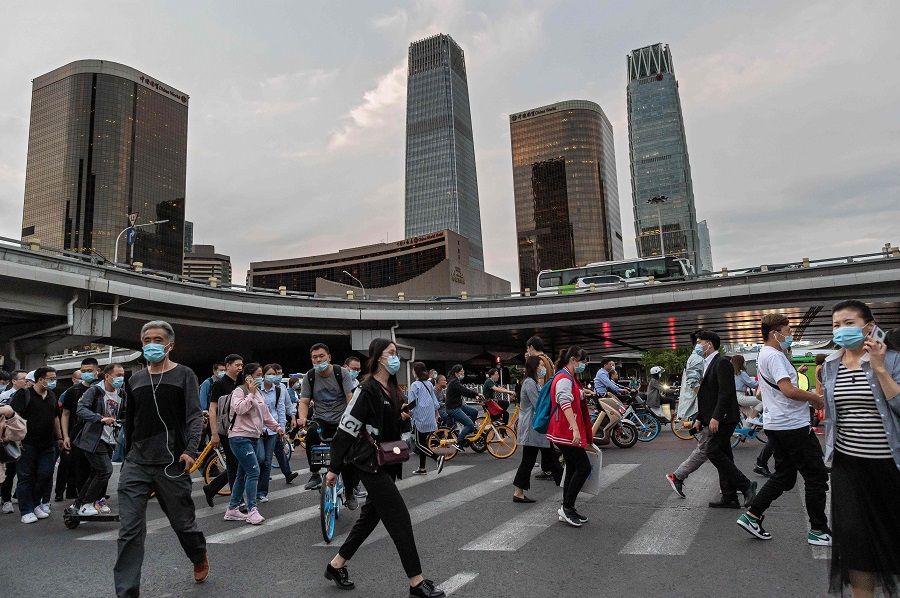 In this picture taken on 22 September 2020, people cross a road during the evening rush hour in Beijing. (Nicolas Asfouri/AFP)