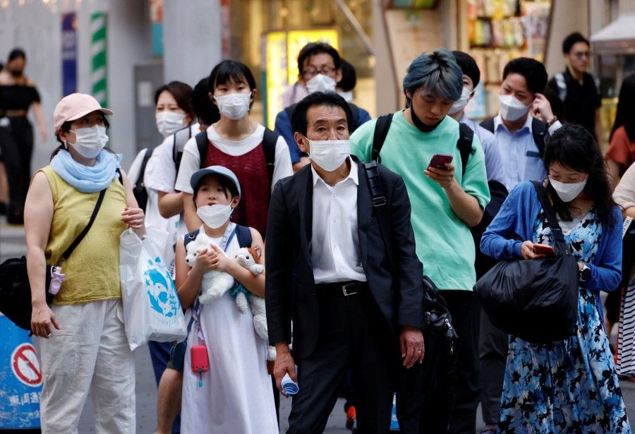 People wearing protective masks amid the Covid-19 outbreak, stand in front of cross walk in Tokyo, Japan, 25 July 2022. (Kim Kyung-Hoon/Reuters)
