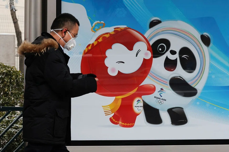 A man wearing a face mask walks past an advertising board featuring Bing Dwen Dwen, the Beijing 2022 Winter Olympic Mascot and Shuey Rhon Rhon, the 2022 Beijing Winter Paralympic Games Mascot, in Beijing, China, 24 January 2022. (Tyrone Siu/Reuters)