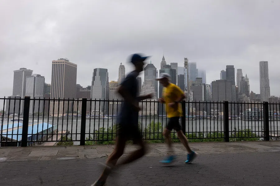 People walk and run along the Brooklyn promenade as Manhattan sits under a layer of heavy clouds on 9 August 2024, in New York City. (Spencer Platt/Getty Images via AFP)