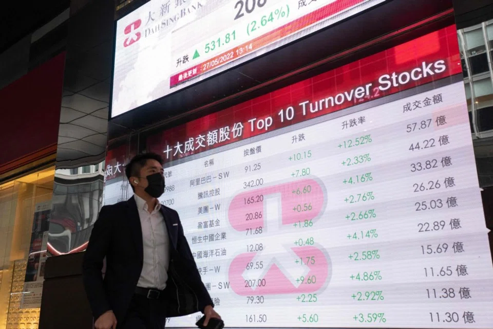 A man walks past an electronic display showing the Hang Seng Index in the Central district of Hong Kong on 27 May 2022. (Bertha Wang/AFP)