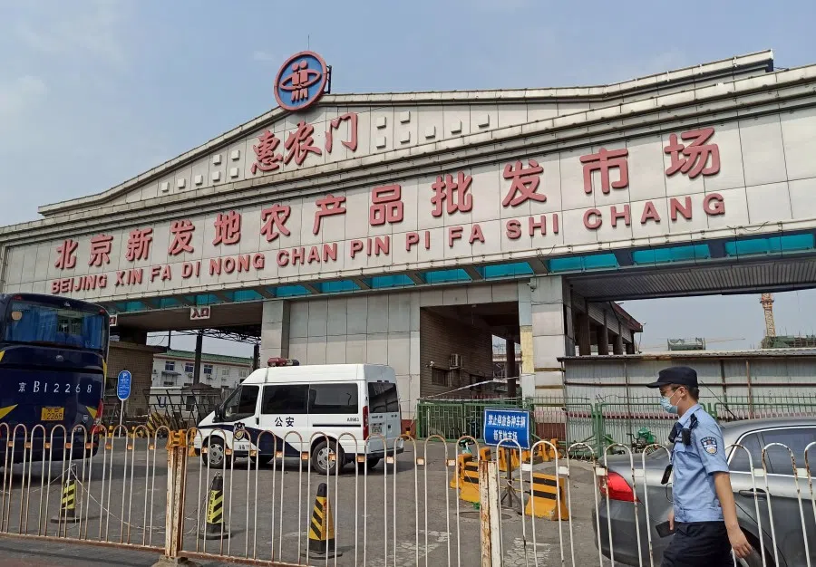A police officer wearing a face mask is seen outside an entrance of the Xinfadi wholesale market, which has been closed for business after new coronavirus infections were detected, in Beijing, 13 June 2020. (CNS via REUTERS)