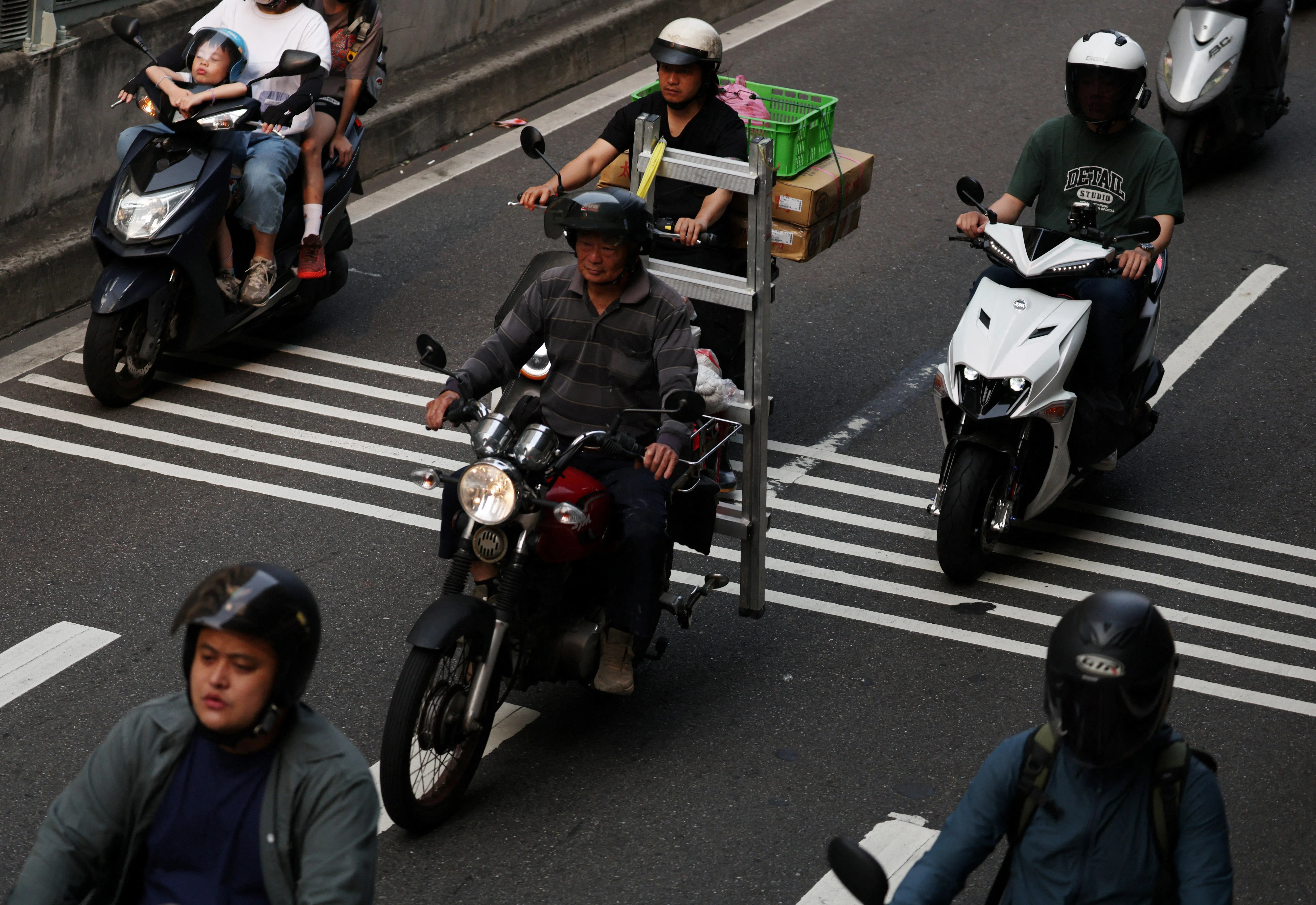 Motorists carrying goods take the ramp off Taipei Bridge, at a location known to locals as the Scooter Waterfall, during morning rush hour in Taipei, Taiwan on 15 April 2026. (Edgar Su/Reuters)