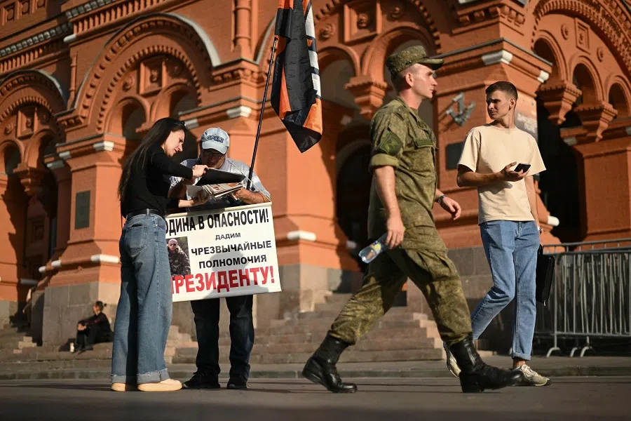 An activist from the pro-Kremlin movement with a placard reading “The homeland is in danger! Let’s give emergency powers to the president!” pickets in central Moscow on 9 September 2024. (Natalia Kolesnikova/AFP)