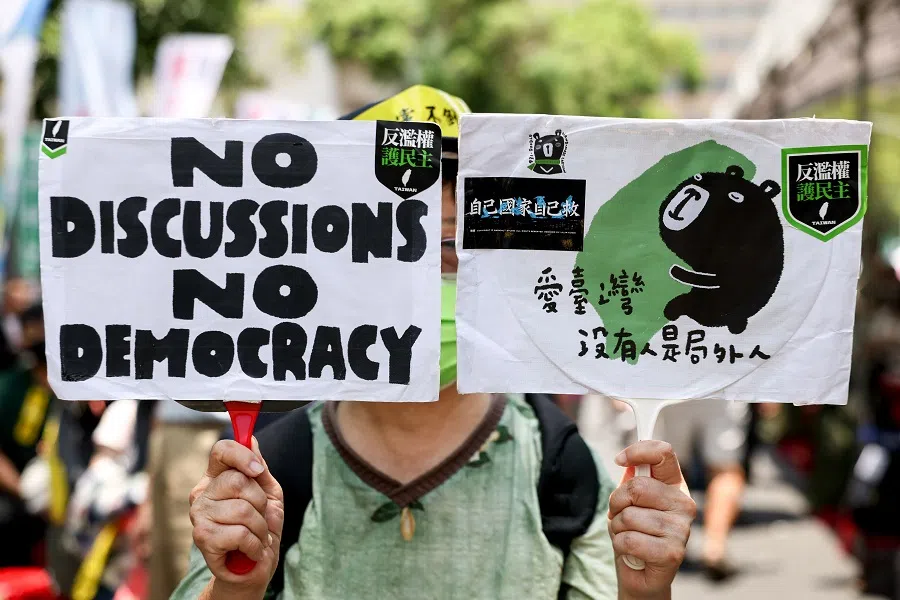 A supporter of the Democratic Progressive Party (DPP) with boards reading “No discussion no democracy” and “Love Taiwan, there’s no one can be ruled out” during the voting for reconsidering controversial bills at Parliament, in Taipei, Taiwan, on 21 June 2024.