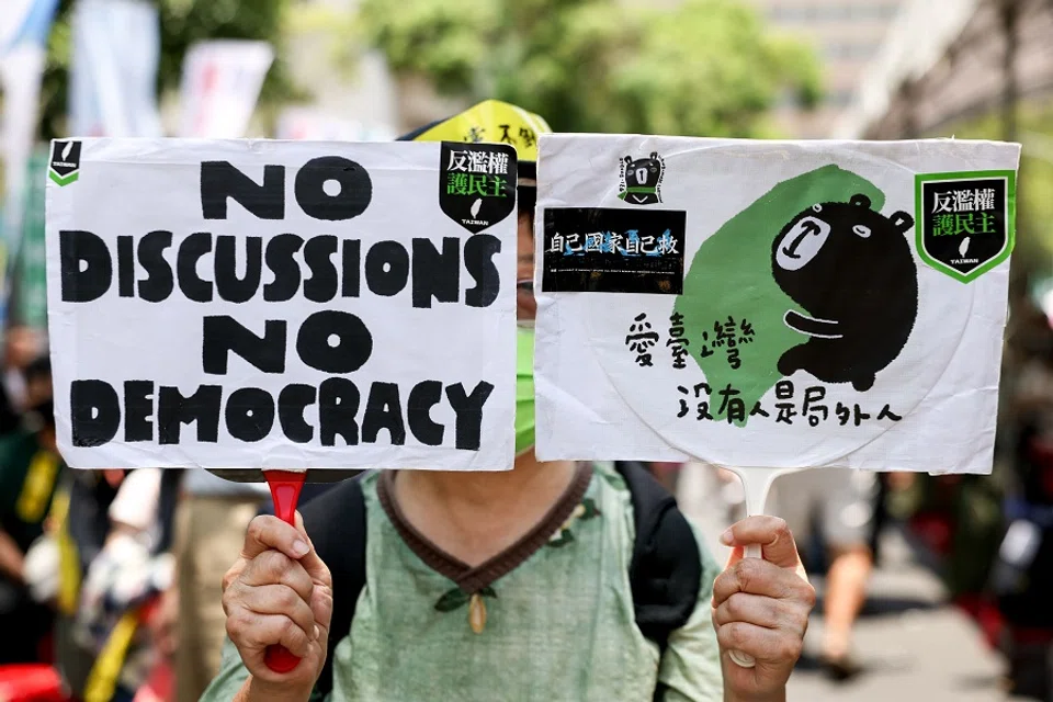 A supporter of the Democratic Progressive Party (DPP) with boards reading “No discussion no democracy” and “Love Taiwan, there’s no one can be ruled out” during the voting for reconsidering controversial bills at Parliament, in Taipei, Taiwan, on 21 June 2024. (I-Hwa Cheng/AFP)