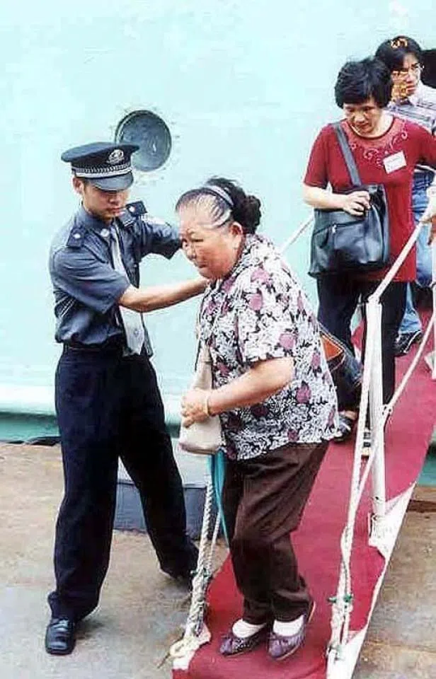 A Taiwanese delegation arriving in Xiamen from Kinmen, 2005. An elderly woman is kindly assisted by a Xiamen customs officer as she disembarks.