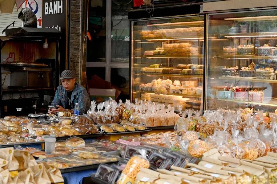 A man uses his mobile phone while waiting for customers at a bakery in Hanoi on 12 January 2026. (Nhac Nguyen/AFP)