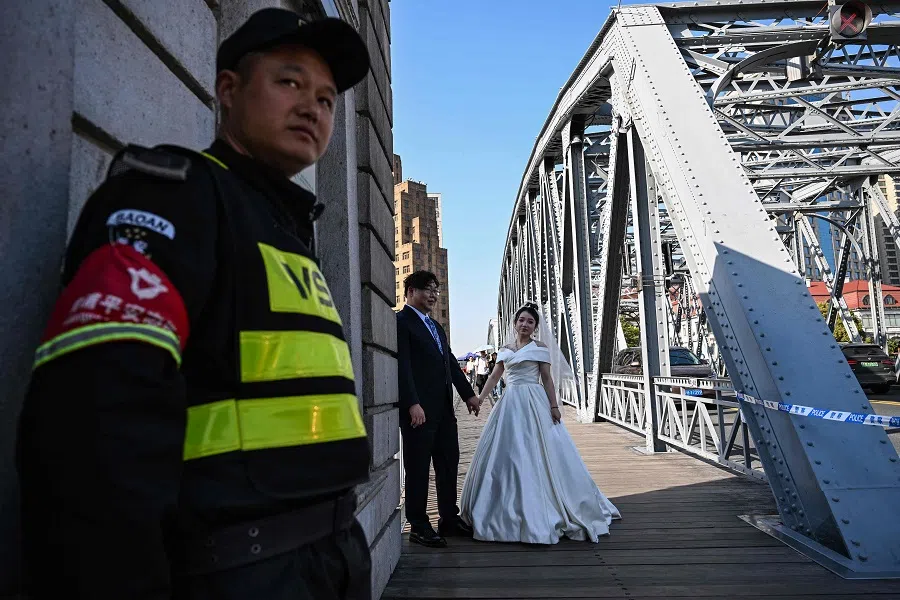 A couple poses during a photo session on the Garden Bridge, in Shanghai, China, on 30 March 2024. (Hector Retamal/AFP)