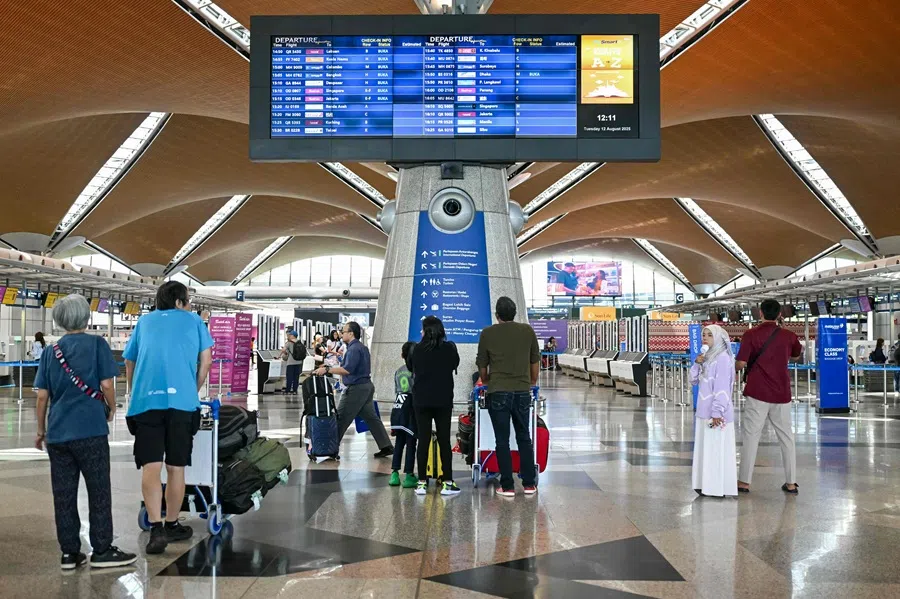 Passengers check the flight information screen at Kuala Lumpur International Airport in Sepang on 12 August 2025.