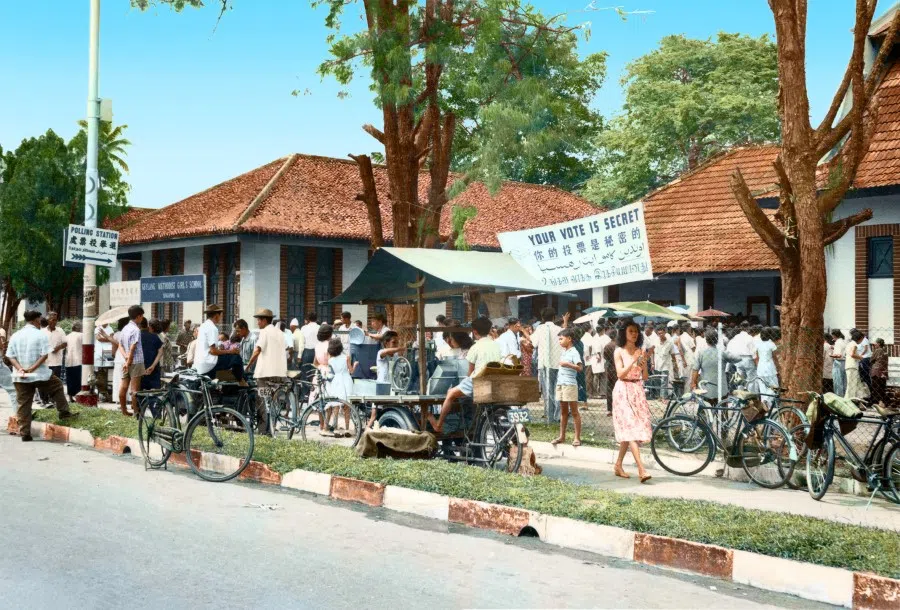 An election in 1968. Many people turned out to vote, and some hawkers set up stalls outside the voting station.