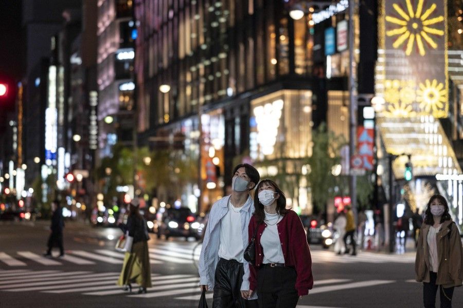 People walk in a street at night in Tokyo on 3 November 2021. (Charly Triballeau/AFP)