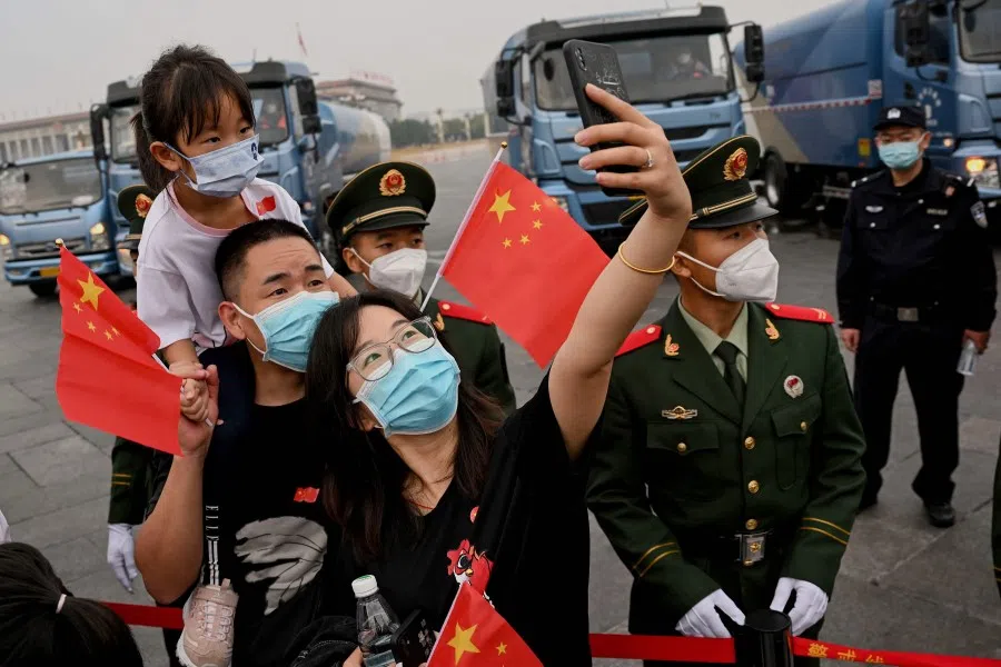 A woman uses a mobile phone to take selfies in front of soldiers at Tiananmen Square after the flag-raising ceremony on China's National Day in Beijing on 1 October 2022. (Noel Celis/AFP)