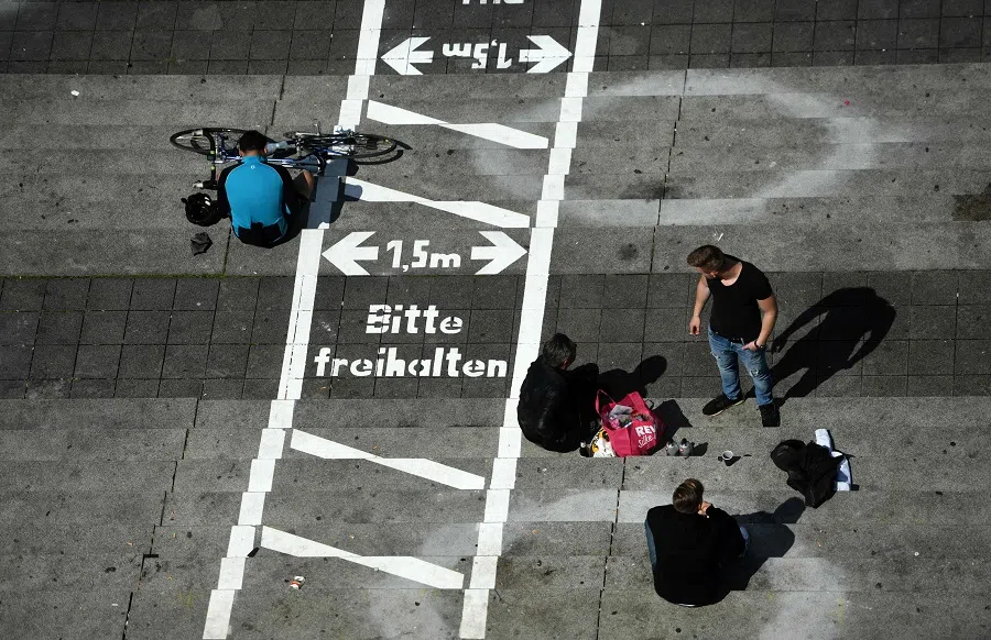 People sit at the stairs of the Burgplatz with painted lines for social distancing at the Rhine promenade in Dusseldorf, Germany, on 12 July 2020. (Ina Fassbender/AFP)