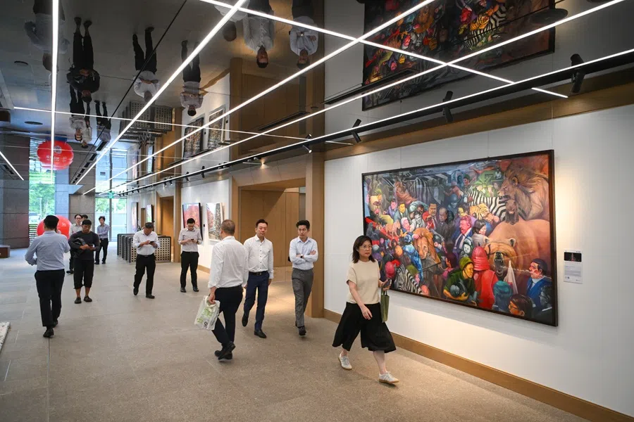 UOB employees walking pass the artworks of 12 UOB Painting of the Year winners, including David Chan’s The Grand History (right), displayed its office in UOB Plaza 1 on 5 August 2025. (SPH Media)