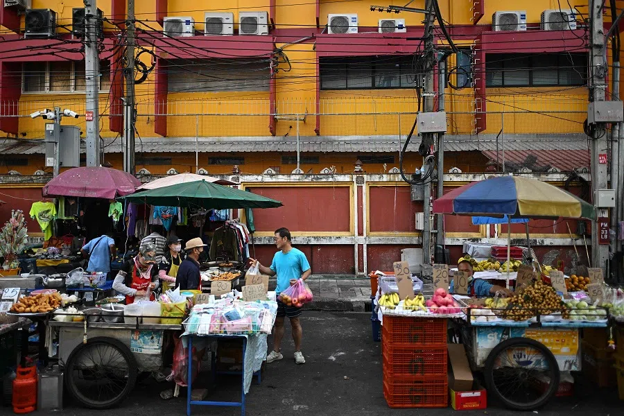 A man (centre) buys food from a vendor at a morning market along a street in Bangkok, Thailand, on 22 January 2025. (Manan Vatsyayana/AFP)