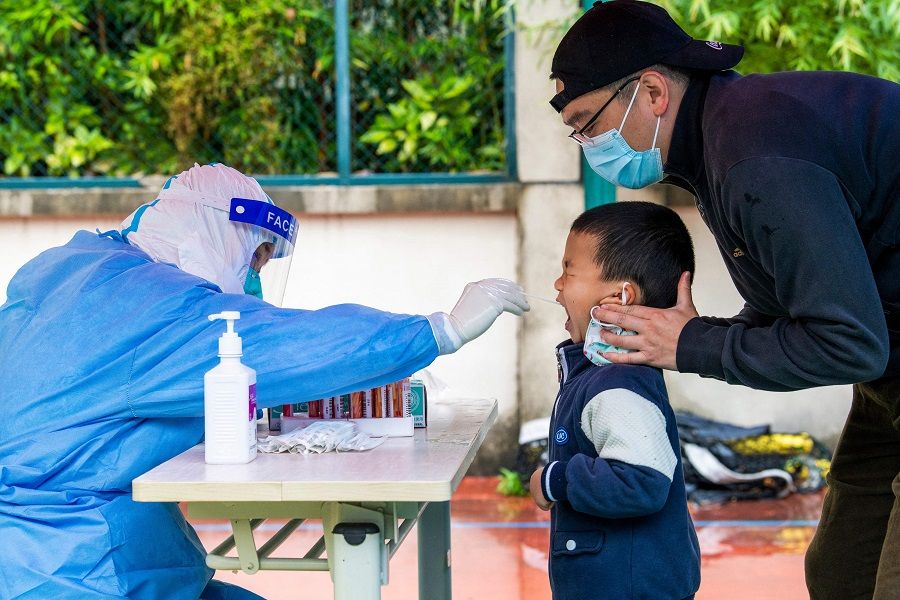 A health worker takes a swab sample from a child to be tested for Covid-19 in a compound under lockdown in the Pudong district in Shanghai, China, on 13 May 2022. (Liu Jin/AFP)