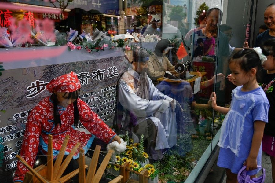 People look at the window of a shoe store in Beijing on 15 August 2023. (Pedro Pardo/AFP)