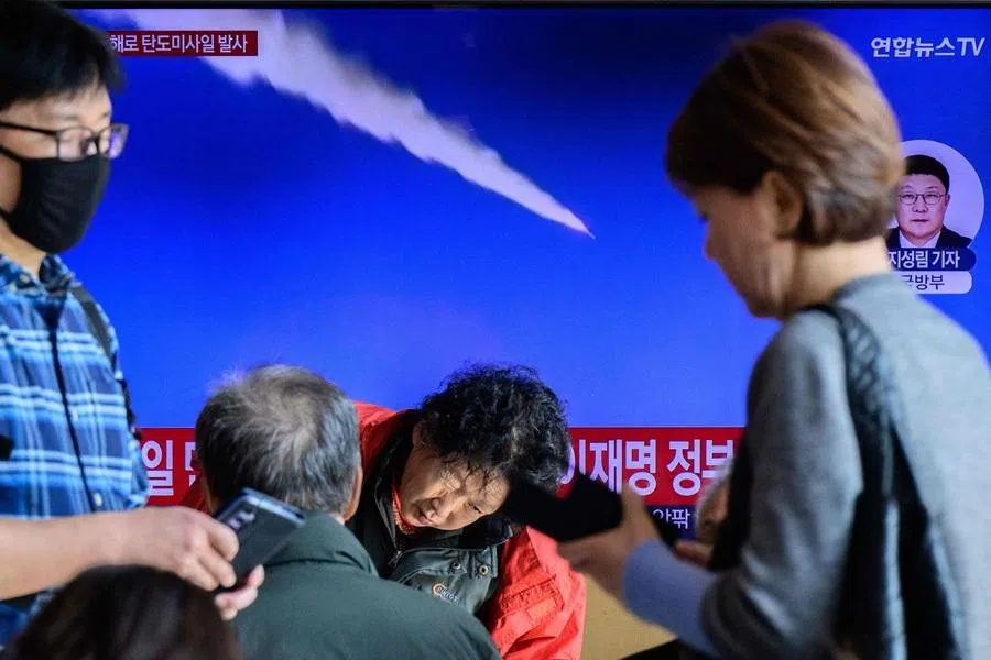 People walk past a television showing a news broadcast with file footage of a North Korean missile test, at a railway station in Seoul on 7 November 2025. (Anthony Wallace/AFP)
