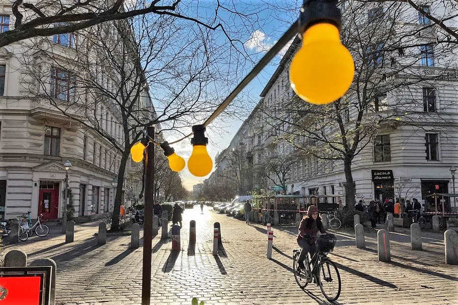 A woman cycles a bicycle down a sun-soaked street in Berlin's Kreuzberg district , Germany, on 2 December 2021. (David Gannon/AFP)