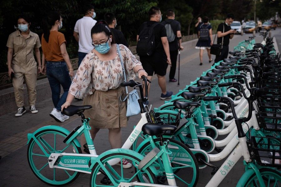 A woman takes a shared bicycle to commute during rush hour in Beijing on 2 September 2020. (Nicolas Asfouri/AFP)