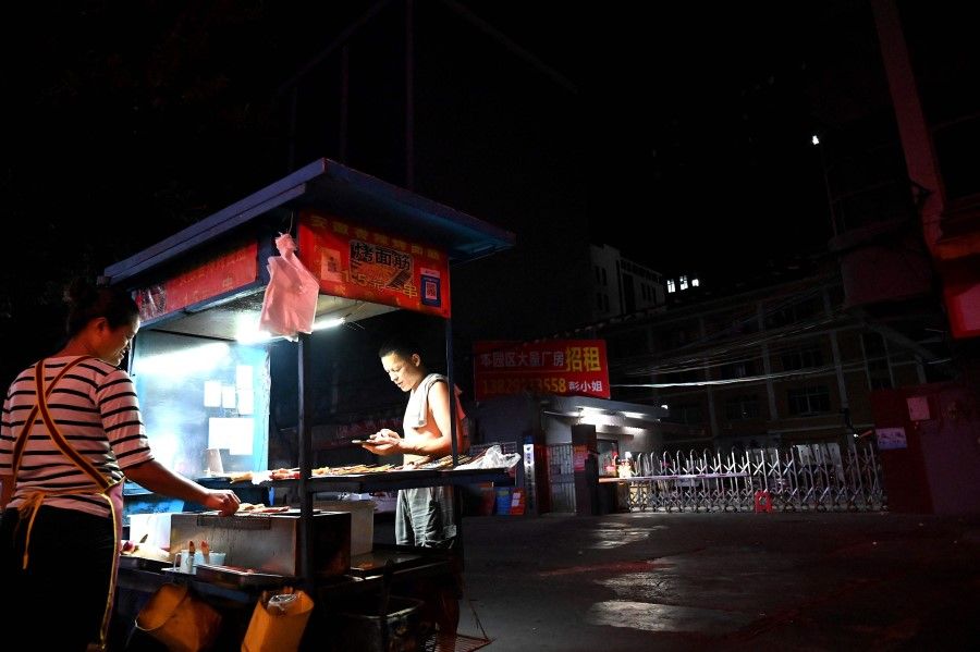 A vendor cooks barbecues at the entrance of an industrial park in Houjie, in Dongguan China's southern Guangdong province on 30 September 2021, an area hit by power restrictions. (Noel Celis/AFP)