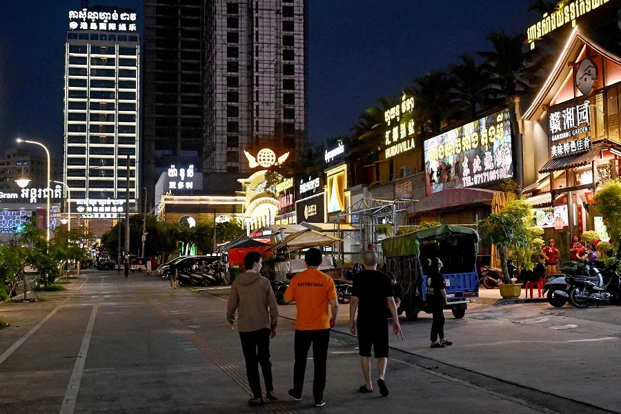 This photo taken on 8 April 2025 shows people walking past Chinese restaurants and shops in Sihanoukville, Cambodia. (Tang Chhin Sothy/AFP)