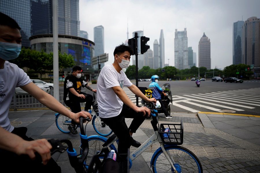 People wearing face masks ride shared bicycles at an intersection in Lujiazui financial district, after the lockdown placed to curb the Covid-19 outbreak was lifted in Shanghai, China, 2 June 2022. (Aly Song/Reuters)