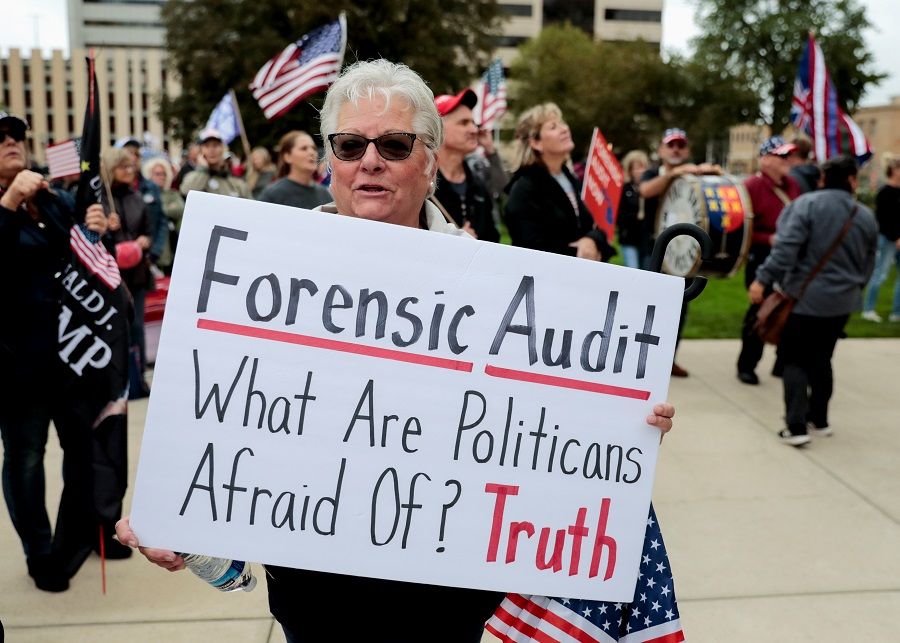 A supporter of former US President Donald Trump holds a sign outside the Michigan State Capitol to demand an audit of 2020 election votes, in Lansing, Michigan, US, 12 October 2021. (Rebecca Cook/Reuters)