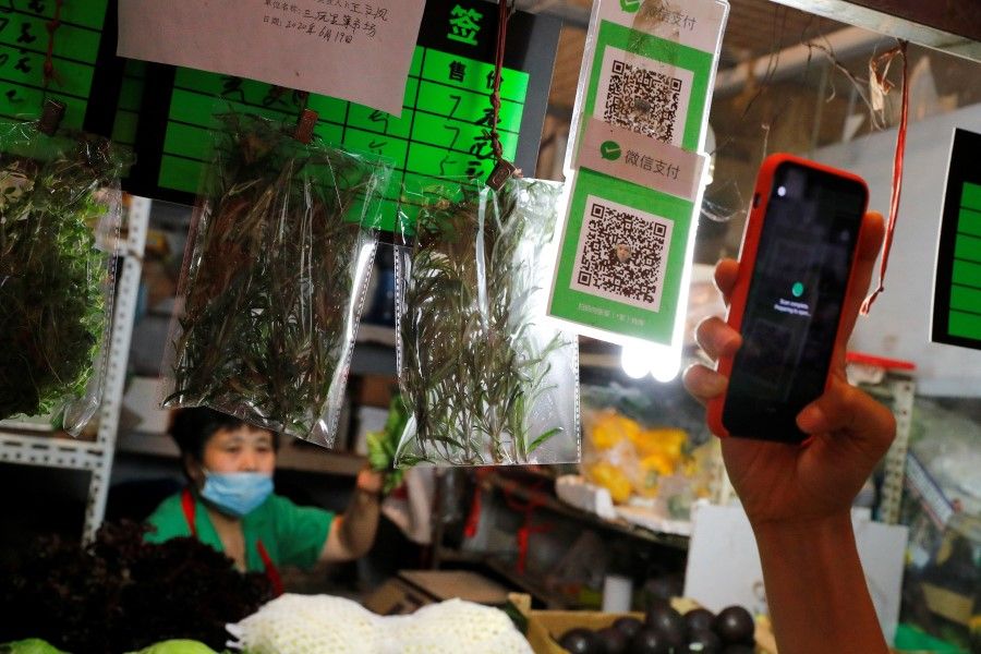 A person scans the QR code of the digital payment services WeChat Pay at a fresh market in Beijing, 8 August 2020. (Thomas Peter/REUTERS)