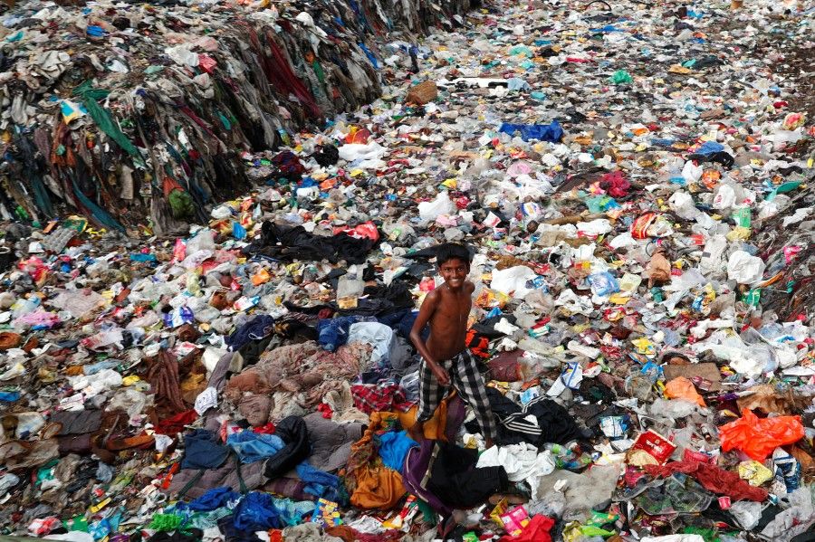 A boy plays on a pile of garbage covering a drain at a slum area on World Environment Day in New Delhi, India, 5 June 2020. (Adnan Abidi/REUTERS)