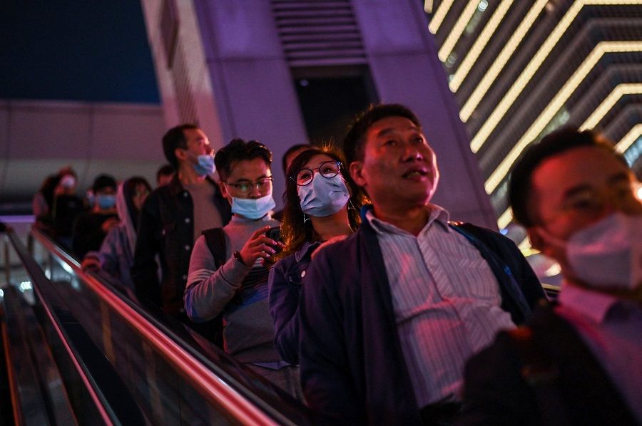 In this picture taken on 25 October 2020, people wearing face masks travel on an escalator in the financial district of Lujiazui in Shanghai, China. (Hector Retamal/AFP)