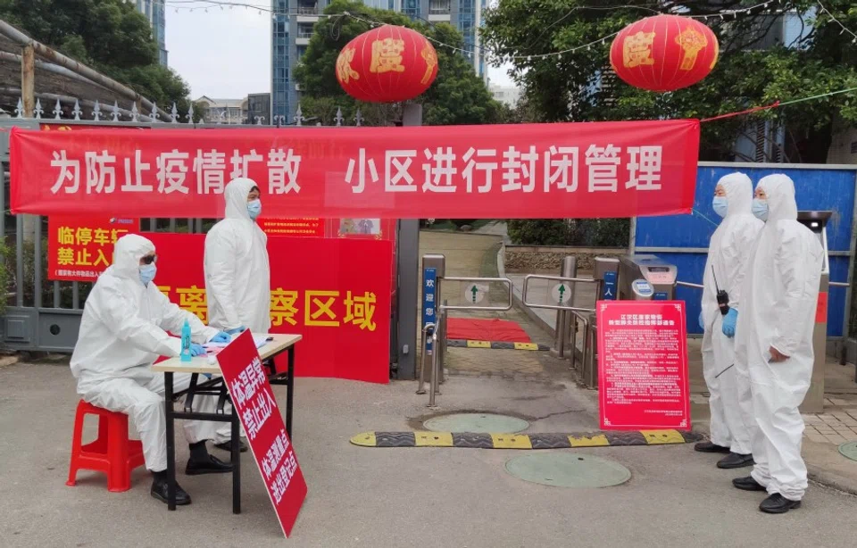 Workers in protective suits at a checkpoint for registration and body temperature measurement, at an entrance to a residential compound in Wuhan. Major leadership changes have been announced in an effort to control the epidemic. (Reuters)