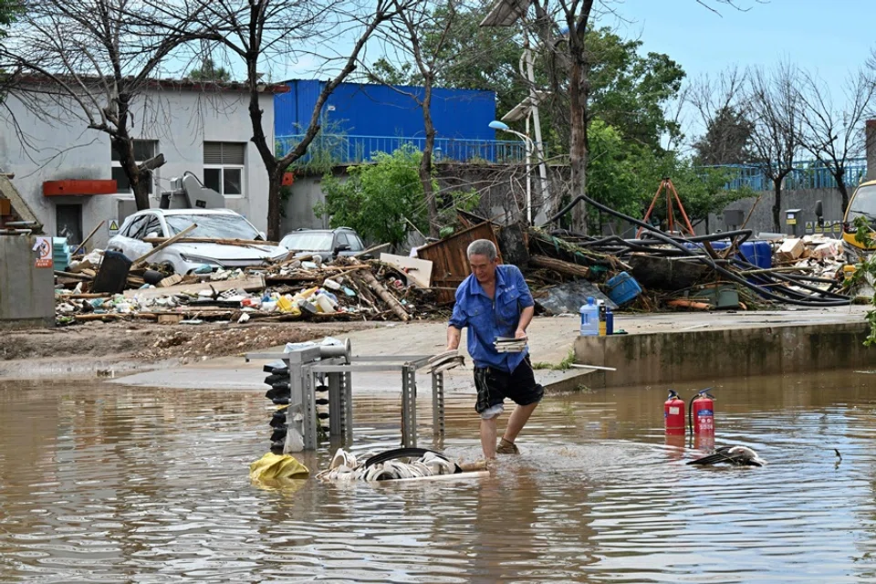 A man salvages items in a flooded area in Miyun district, Beijing, China, on 29 July 2025. (AFP)