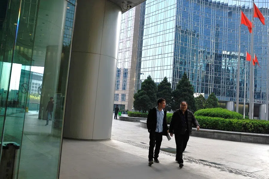 People walk past an office and shopping complex in Beijing, China, on 10 April 2024. (Tingshu Wang/Reuters)