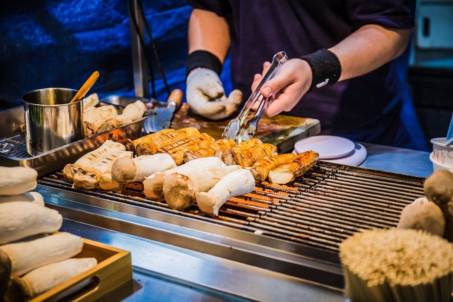 A food stall selling grilled king oyster mushrooms on sticks at the Feng Chia Night Market. (iStock)