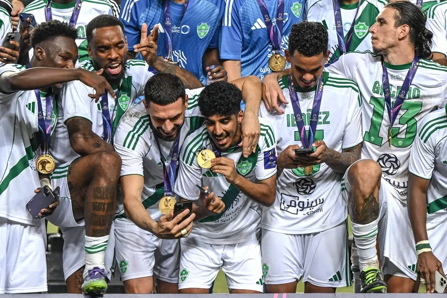 Al-Ahli's players take photographs as they celebrate during the medal ceremony after winning the Saudi Super Cup final football match between Al-Nassr and Al-Ahli at the Hong Kong Stadium in Hong Kong on 23 August 2025. (Wun Suen/AFP)