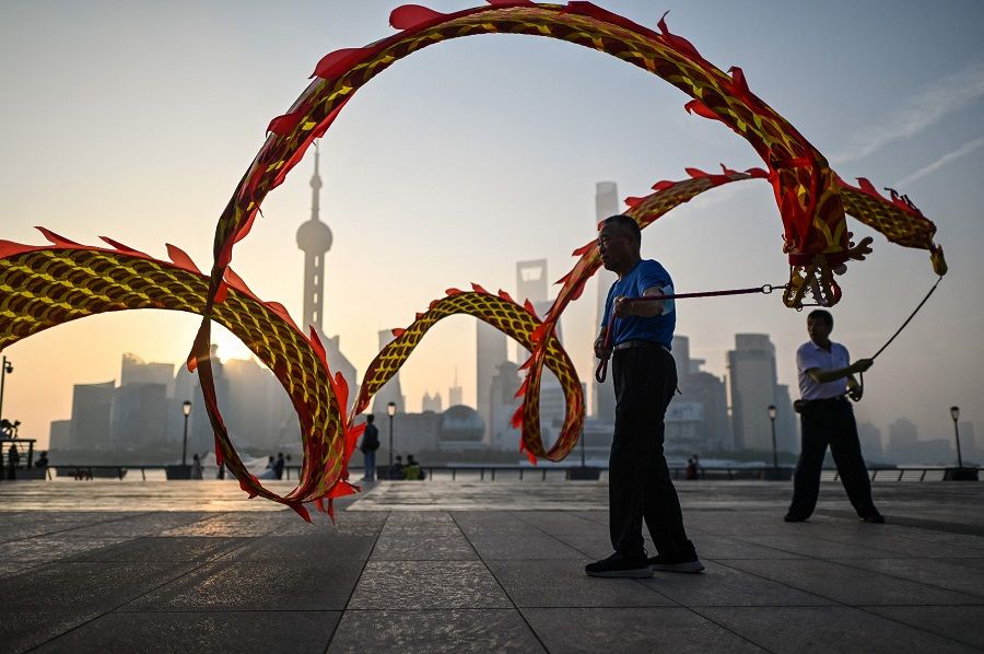 Men twirl dragon streamers on the Bund promenade along the Huangpu River during sunrise in Shanghai, China, on 7 September 2022. (Hector Retamal/AFP)
