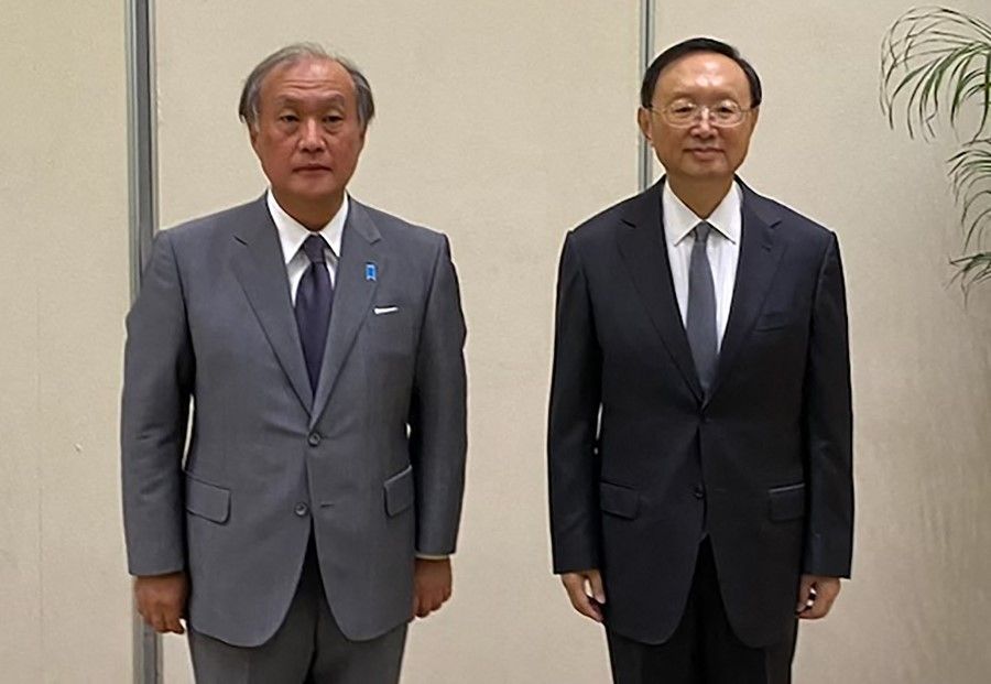 This handout picture taken on 17 August 2022 released by the National Security Agency of Japan on 18 August shows Takeo Akiba (left), secretary-general of Japan's National Security Secretariat, and China's foreign policy chief Yang Jiechi posing for photographs in Tianjin. (Handout/National Security Agency of Japan/AFP)