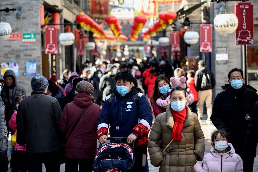 People walk in Qianmen street in Beijing on 17 February 2021. (Noel Celis/AFP)
